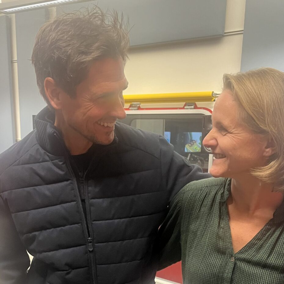 eine Frau und ein Mann haben den Arm umeinander gelegt und blicken einander lachend an